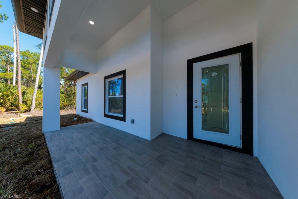 Covered front entry featuring a white exterior, black framed windows, and a glass-paneled entry door