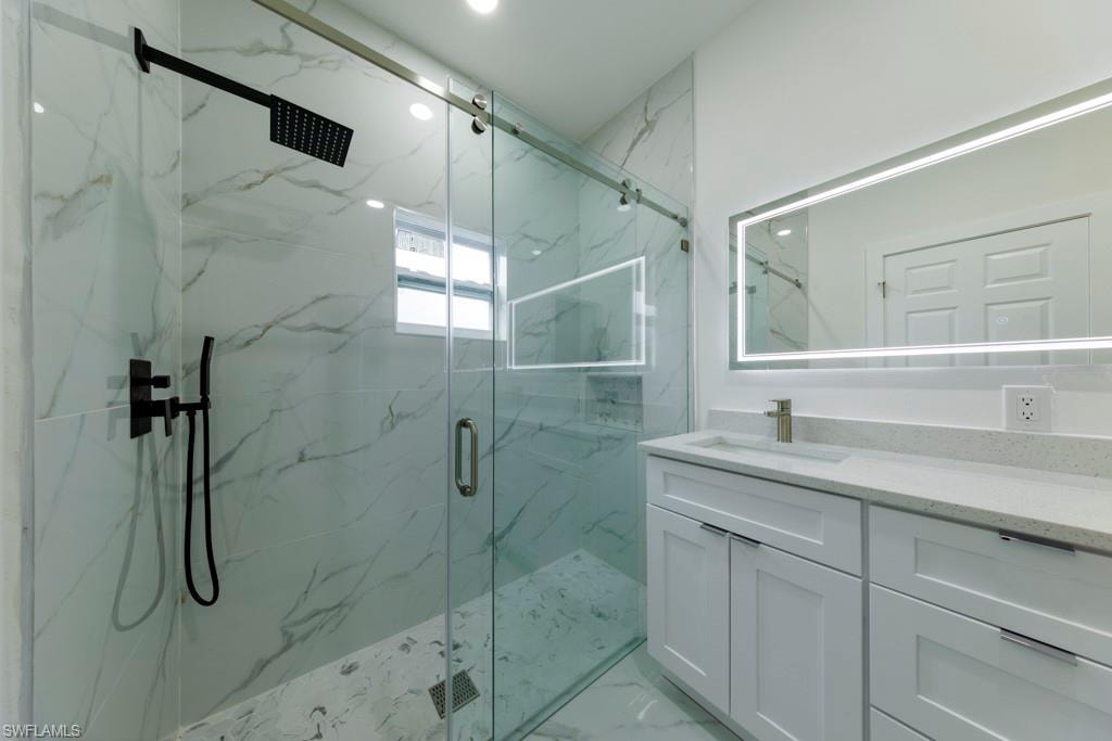 Modern bathroom featuring a spacious glass-enclosed shower with matte black fixtures and a built-in niche