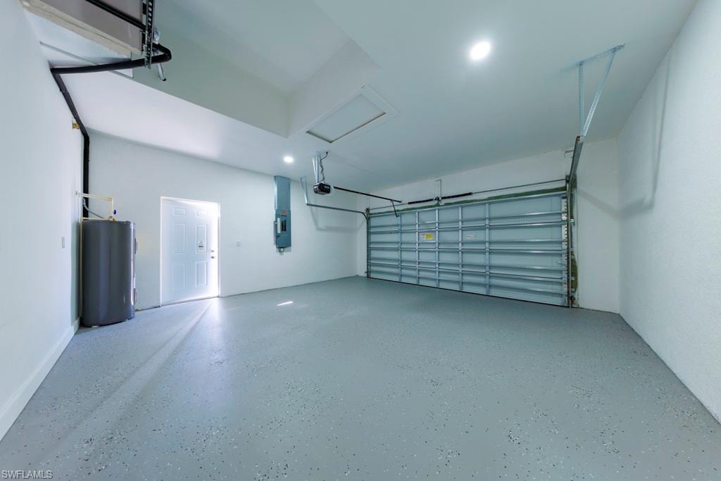 Spacious garage featuring a finished floor coating, an overhead garage door, recessed lighting, and a utility access door