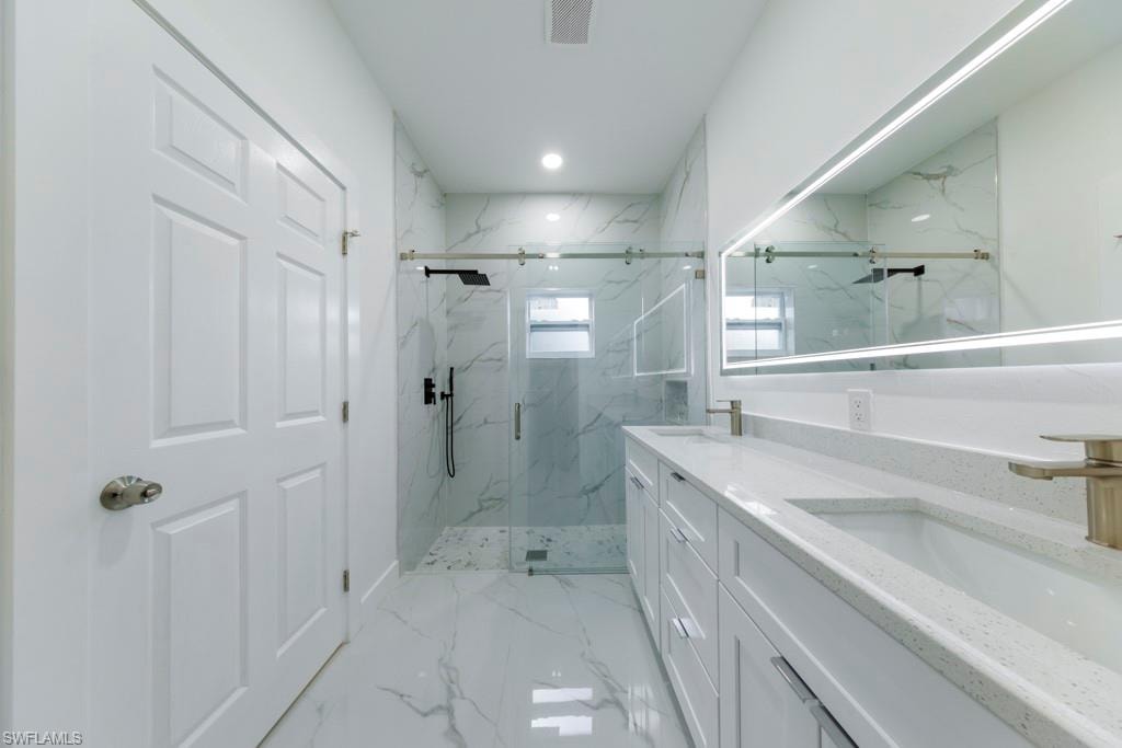 Modern bathroom featuring a dual vanity with white cabinetry, light-toned countertops, and undermount sinks