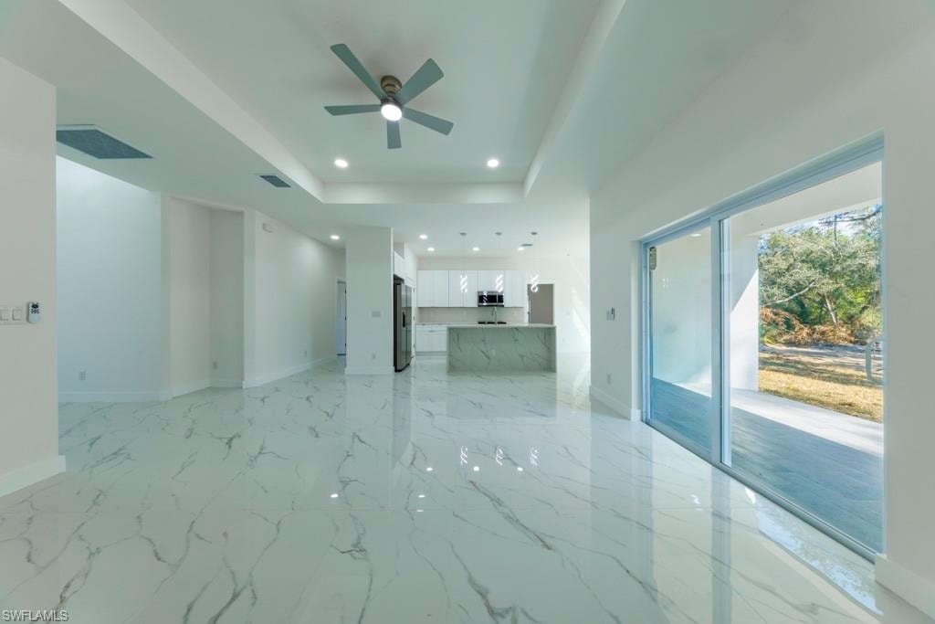 Spacious living area featuring polished marble-look tile flooring, a contemporary ceiling fan, and recessed lighting