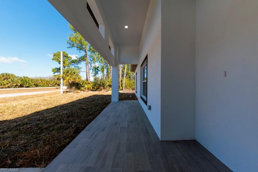 Covered porch featuring wood-finish tile flooring, recessed lighting, and a white stucco exterior