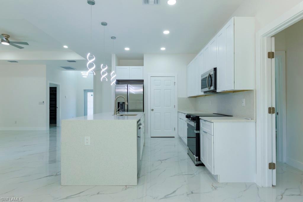 Contemporary kitchen featuring a large island with integrated sink, white cabinetry, and stainless steel appliances