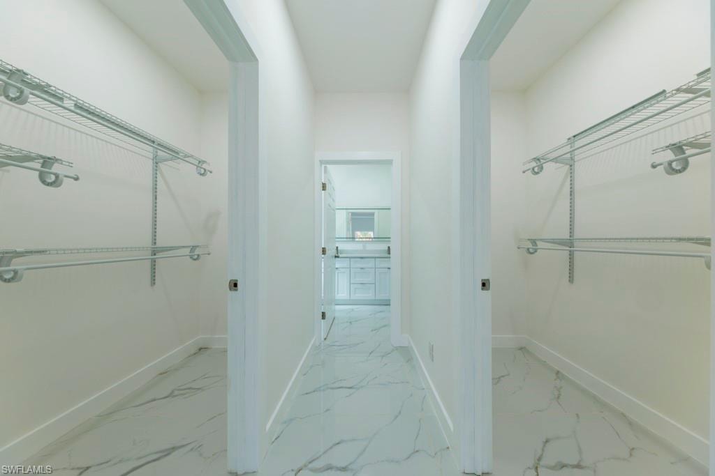Hallway featuring white walls, marble-look tile flooring, and two adjacent wardrobe areas with wire shelving systems