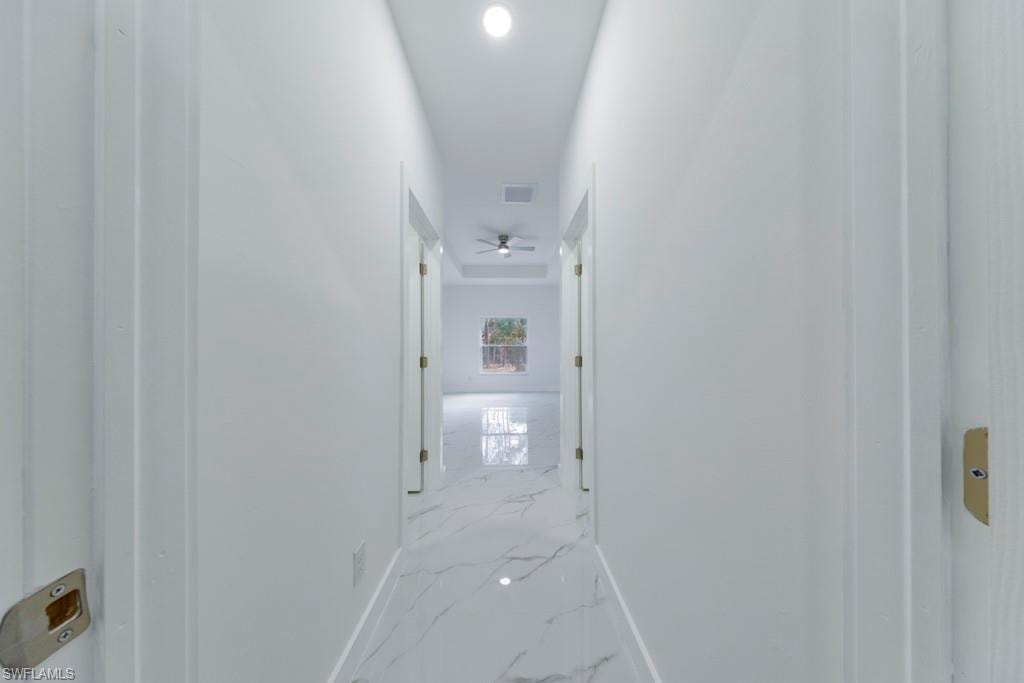 Corridor featuring white walls, recessed ceiling lighting, and large format tile flooring with a marble-like pattern