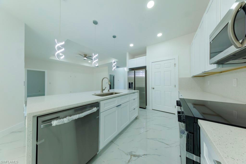 Contemporary kitchen featuring a large island with sink, white shaker cabinetry, stainless steel appliances, quartz countertops, and white tile flooring