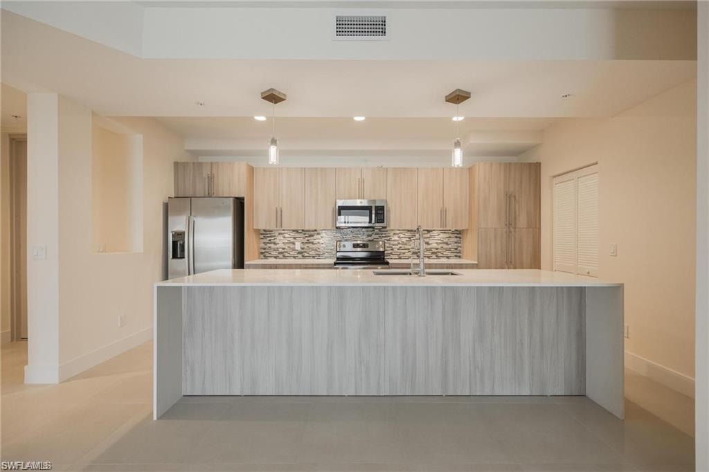 Kitchen featuring baseboards, stainless steel appliances, visible vents, and a sink