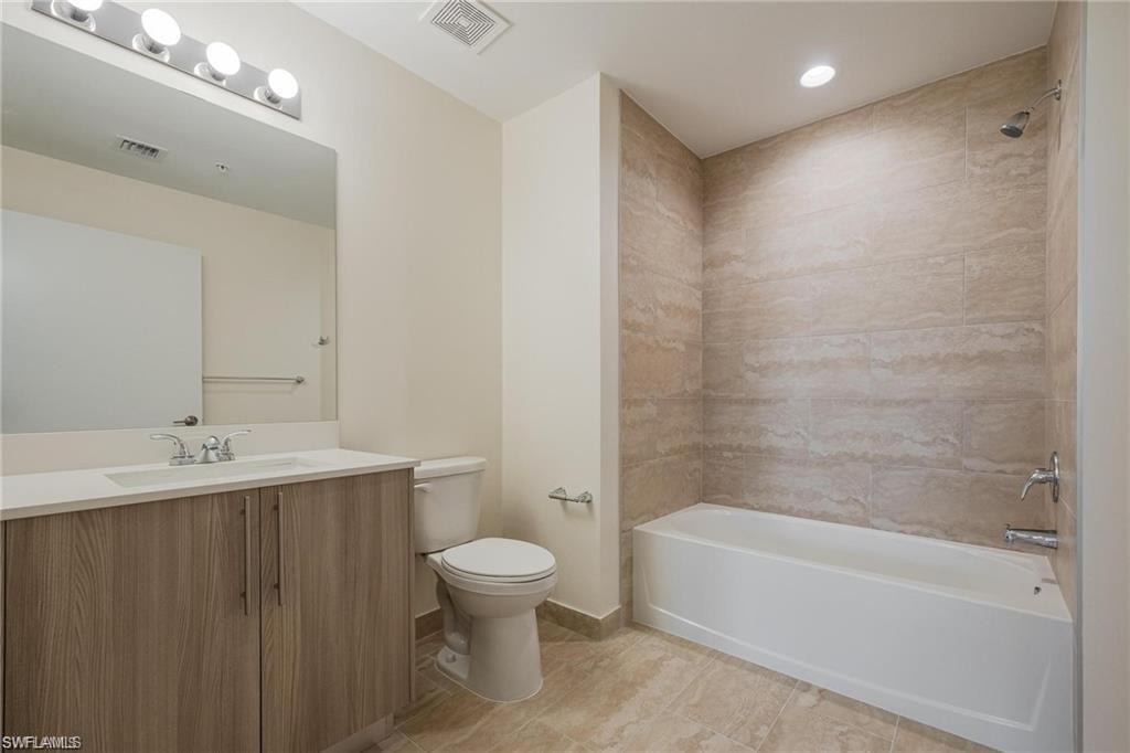 Full bathroom with bathing tub / shower combination, visible vents, vanity, and toilet