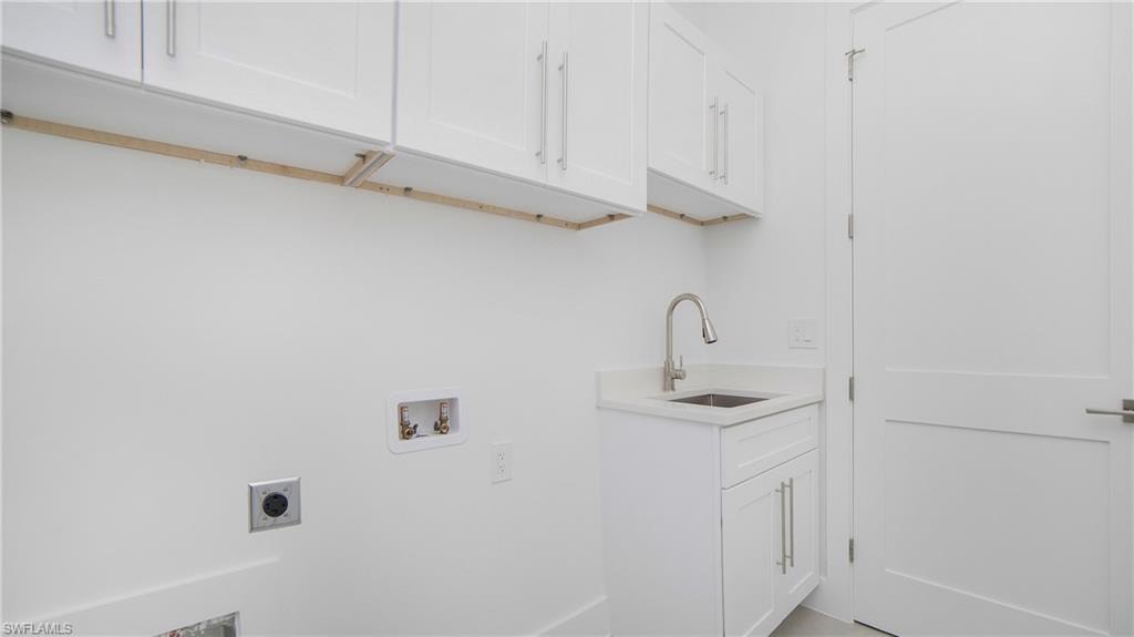 Laundry area featuring white cabinetry, a utility sink with a brushed nickel faucet, and a solid white door with brushed nickel hardware