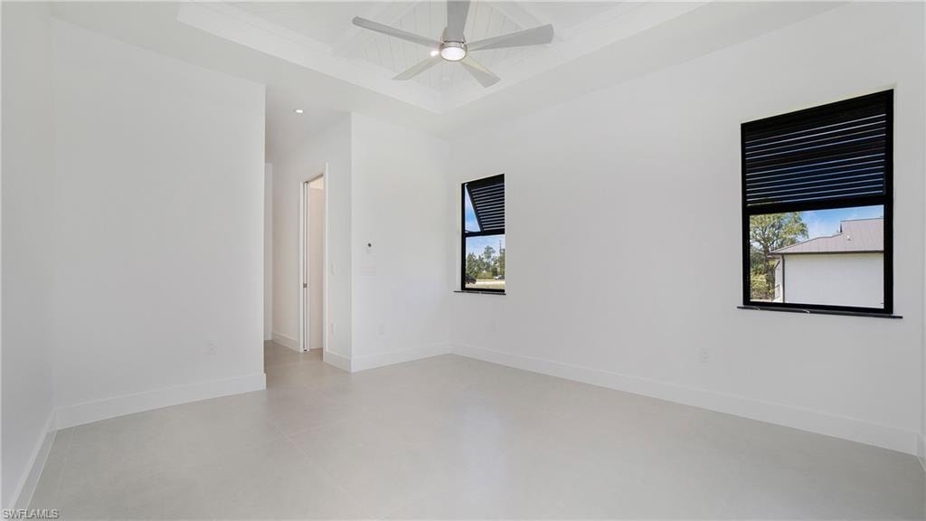 Spacious interior room featuring a tray ceiling, recessed lighting, and a contemporary ceiling fan