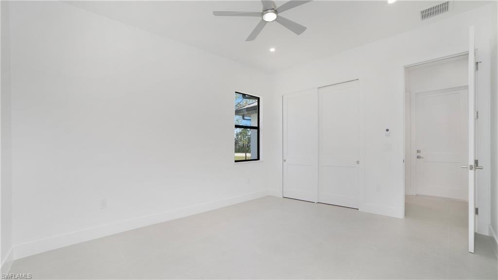 Spacious room featuring light-toned flooring, a window with black trim, a ceiling fan, recessed lighting, and a double sliding closet door