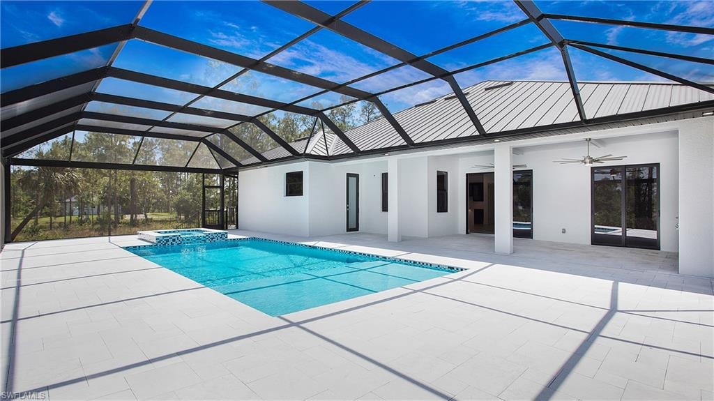 Expansive screened lanai featuring a rectangular swimming pool, integrated spa with mosaic tile, and a large white-tiled patio