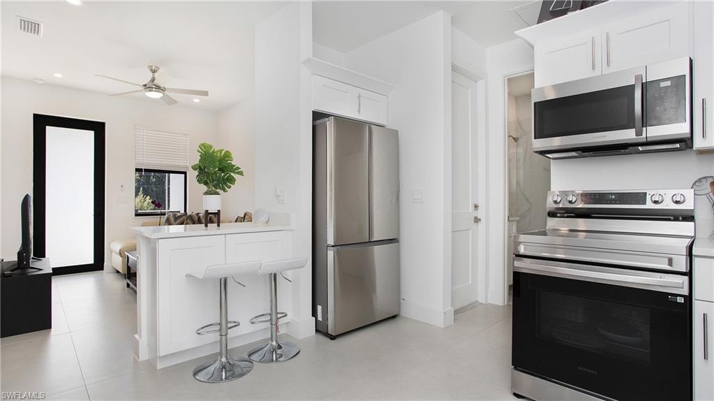 Contemporary kitchen featuring stainless steel appliances, white cabinetry, and light-toned flooring