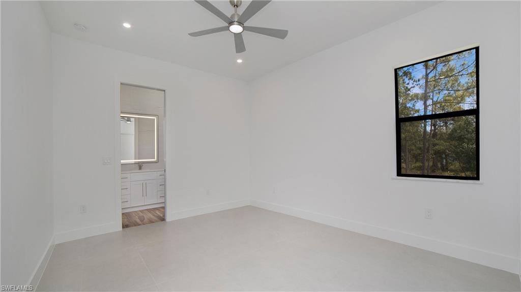 Bright room with light tile flooring, a window offering a wooded landscape, and a ceiling fan with integrated lighting
