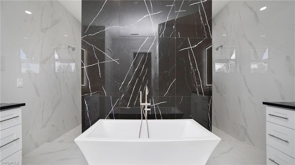 Freestanding soaking tub with a floor-mounted brushed nickel tub filler