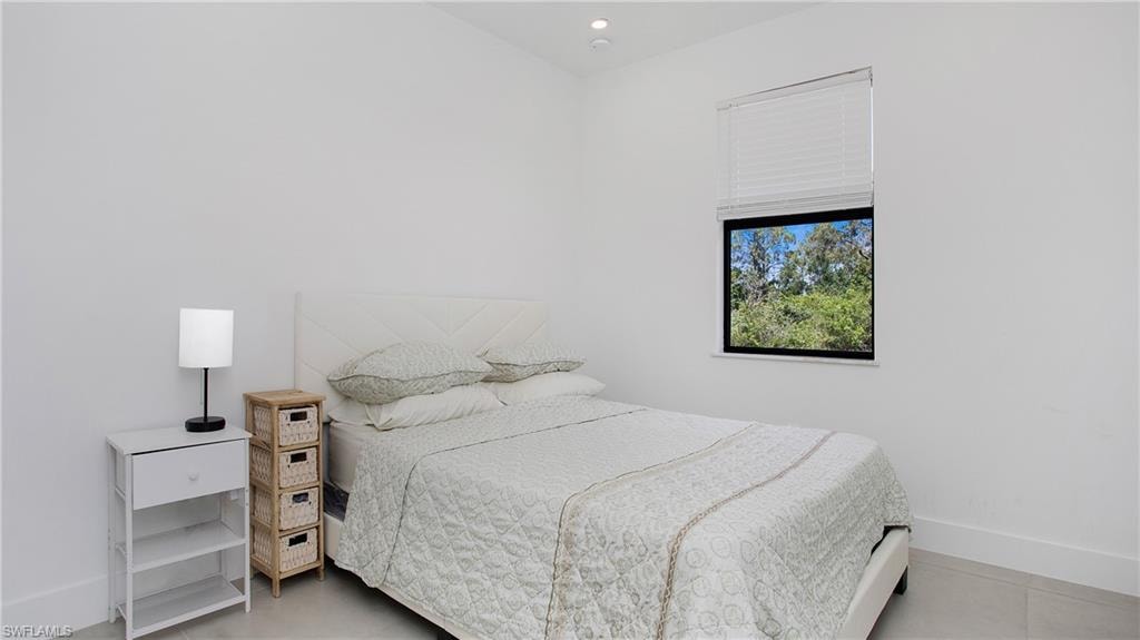 Bright interior space featuring a single window with blinds and a dark frame