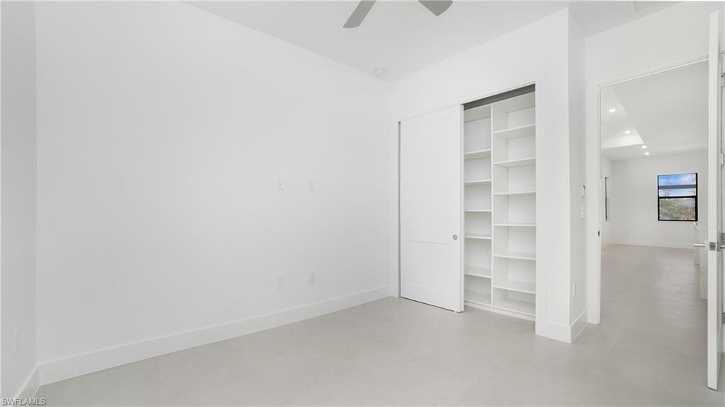 Recessed closet with integrated shelving, sliding panel doors, high ceilings, and light-toned flooring