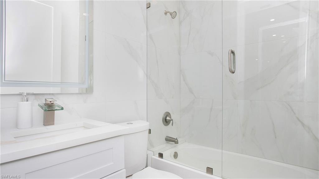 White bathroom featuring a glass-enclosed tub and shower combination