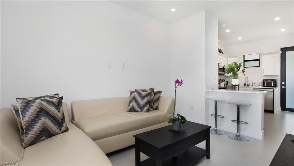 Open-concept living area featuring recessed lighting, a breakfast bar, stainless steel appliances, and a dark-framed glass paneled door