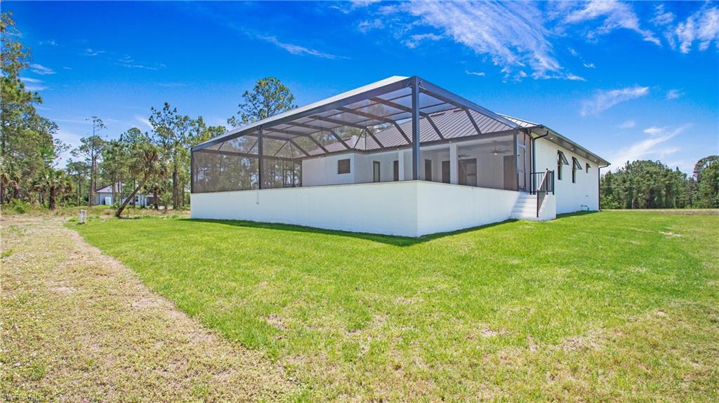 Expansive screened lanai featuring an open-air ceiling, ceiling fans, white exterior walls, and black railings
