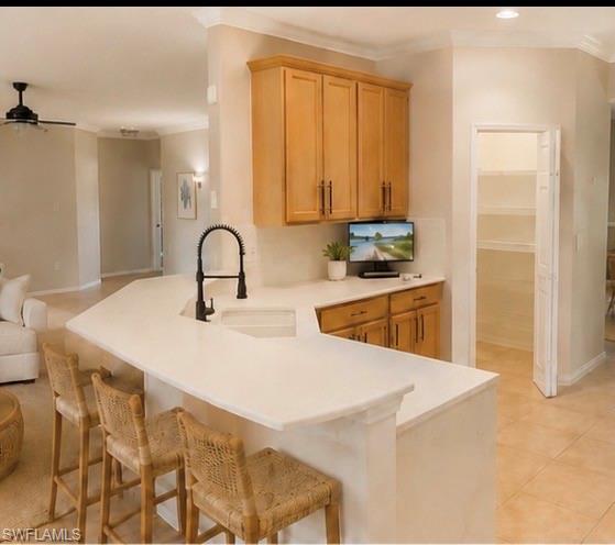 Kitchen island featuring a built-in sink with a matte black faucet, light-toned countertops, and integrated seating