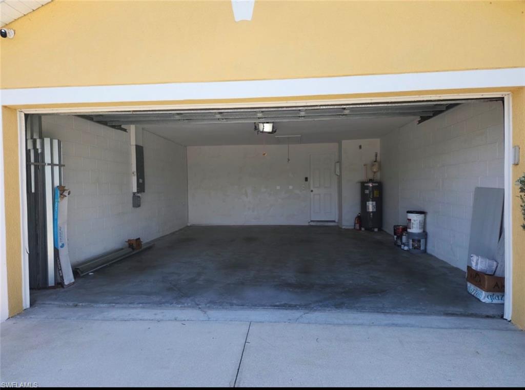 Two-car garage with a concrete floor, painted block walls, and an interior access door