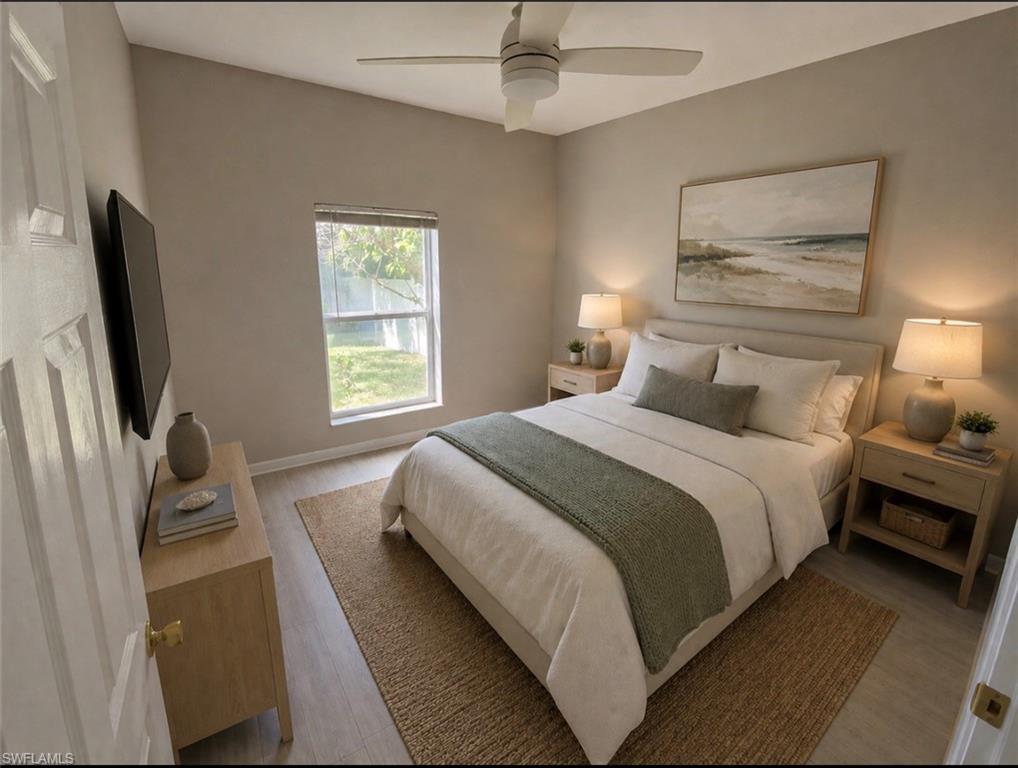 Bedroom featuring vaulted ceilings, wood-finish flooring, a ceiling fan, and a single window overlooking exterior green space