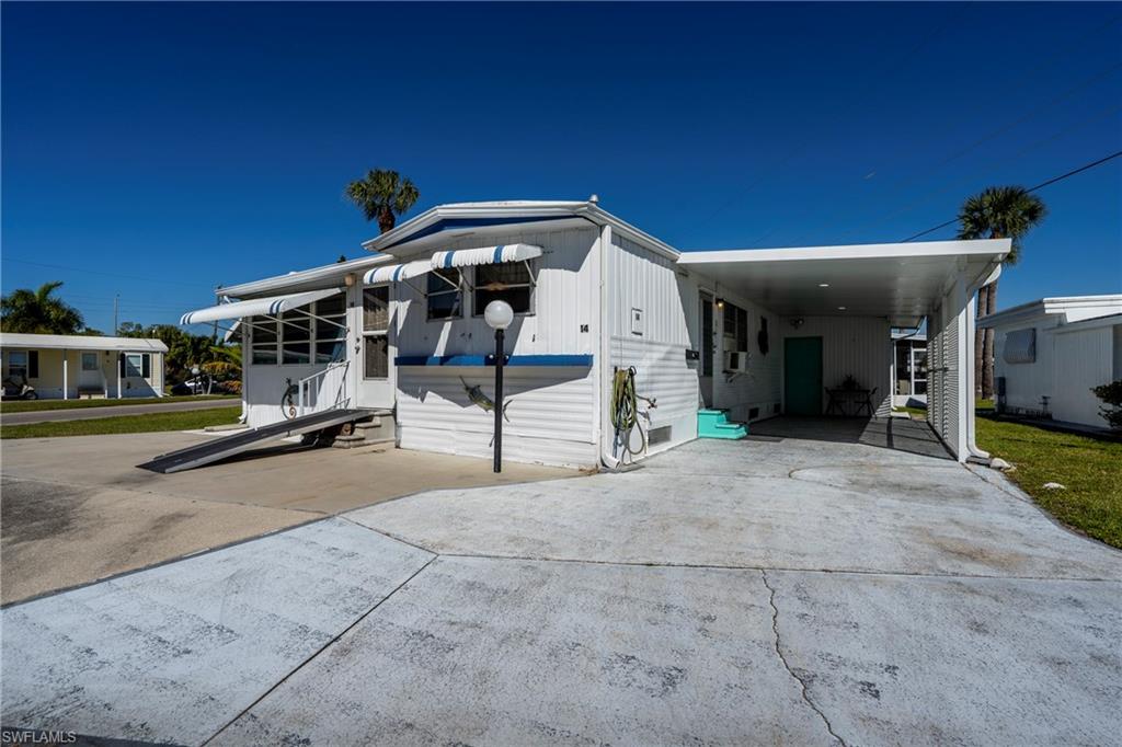 View of front of property featuring driveway, an attached carport, and entry steps