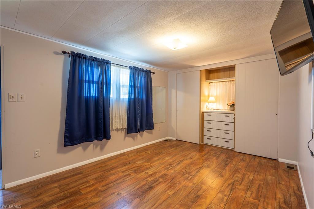 Primary bedroom with wood-style floors and closets