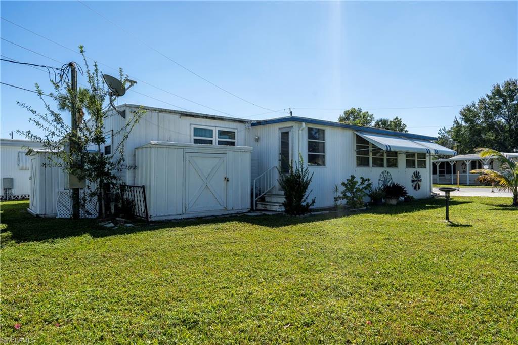 View of property exterior featuring a lawn, shed, and side door entrance