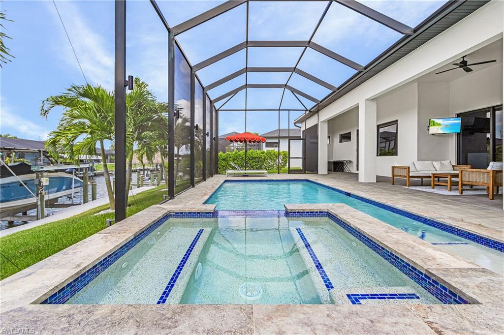 Screened outdoor living area featuring a pool and integrated spa