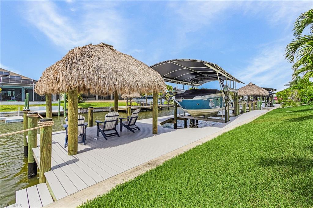 Waterfront property featuring a private dock with multiple boat slips, a covered boat lift, and a tiki hut
