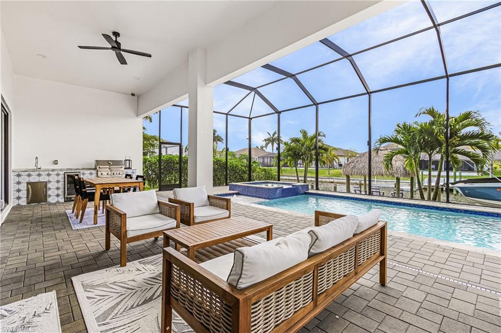 Screened lanai featuring a swimming pool, integrated spa, and an outdoor kitchen with a built-in grill and sink