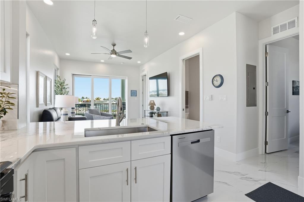 Kitchen with open floor plan, stainless steel dishwasher, white cabinetry, light stone counters, and recessed lighting - Virtually Edited Image