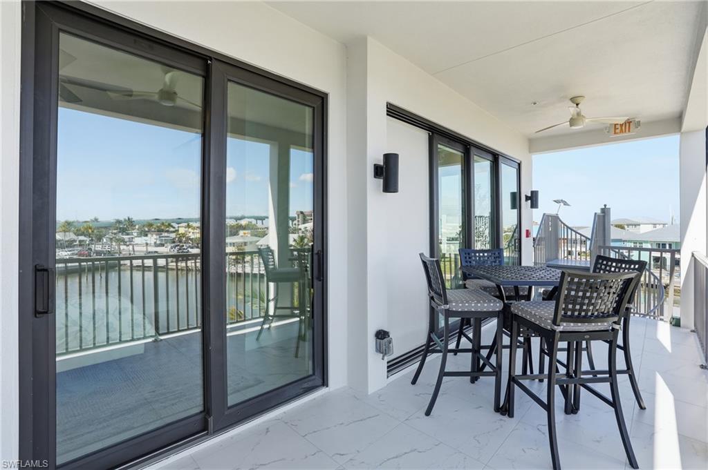 Balcony with a water view, a ceiling fan, and outdoor dining space - Virtually Edited Image