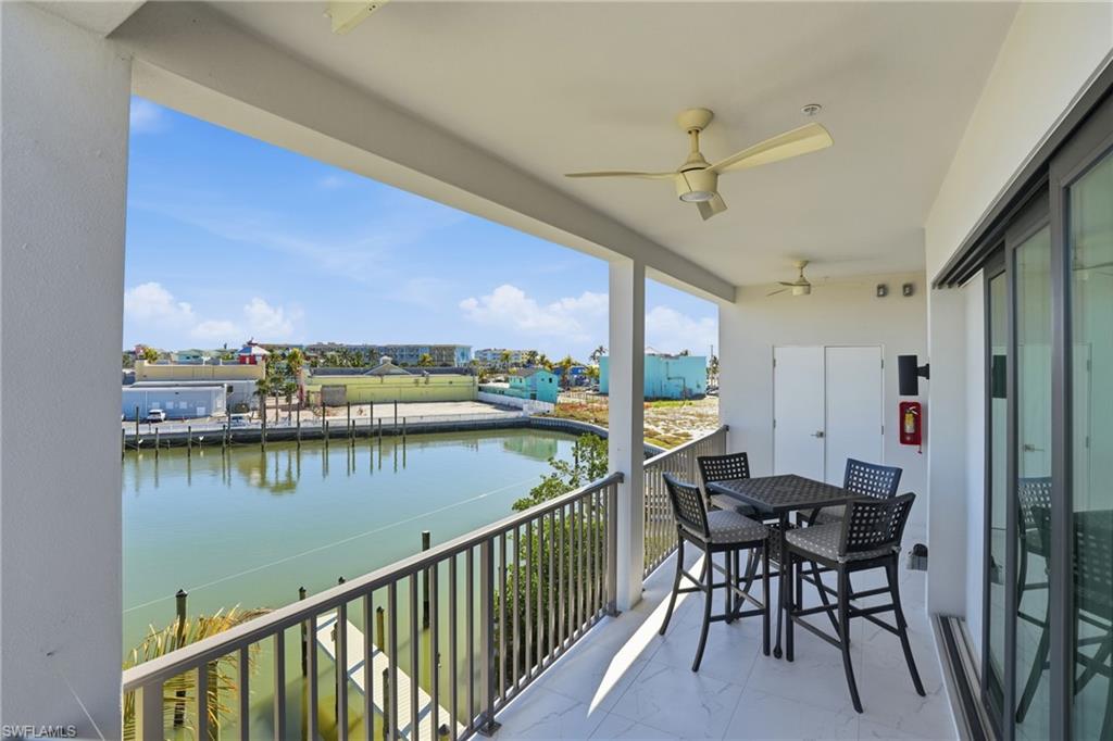 Balcony with a water view, a ceiling fan, and outdoor dining area - Virtually Edited Image