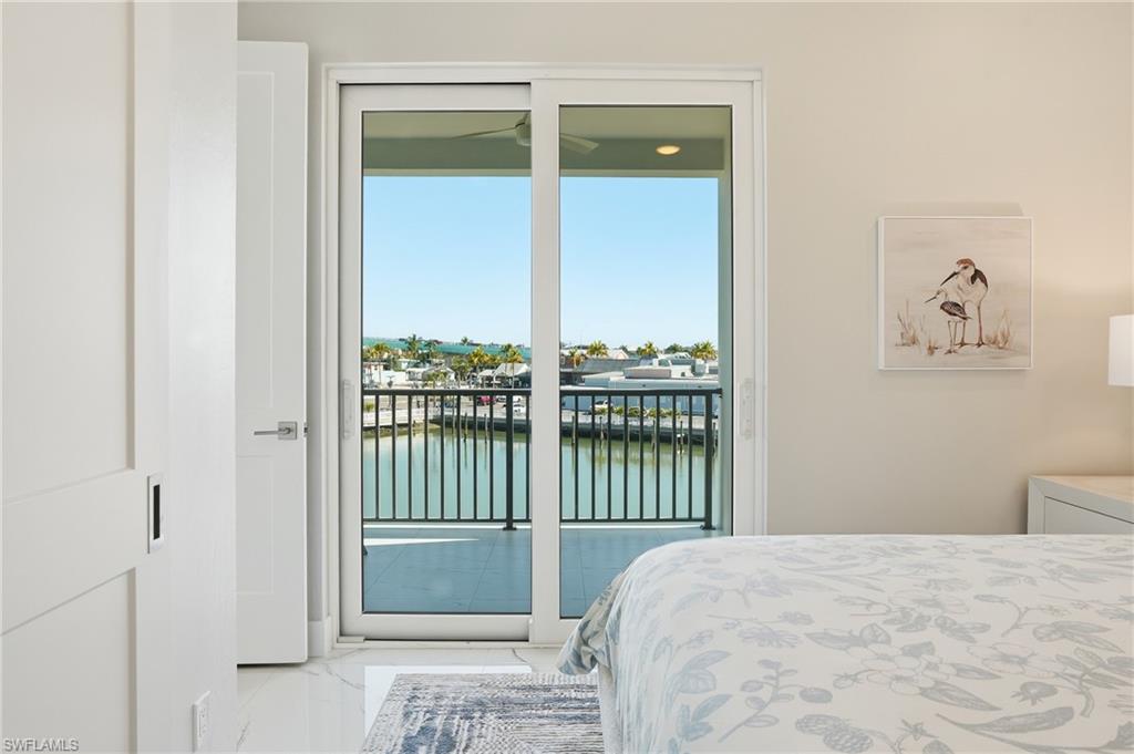 Bedroom featuring a water view, light marble finish flooring, and access to outside - Virtually Edited Image