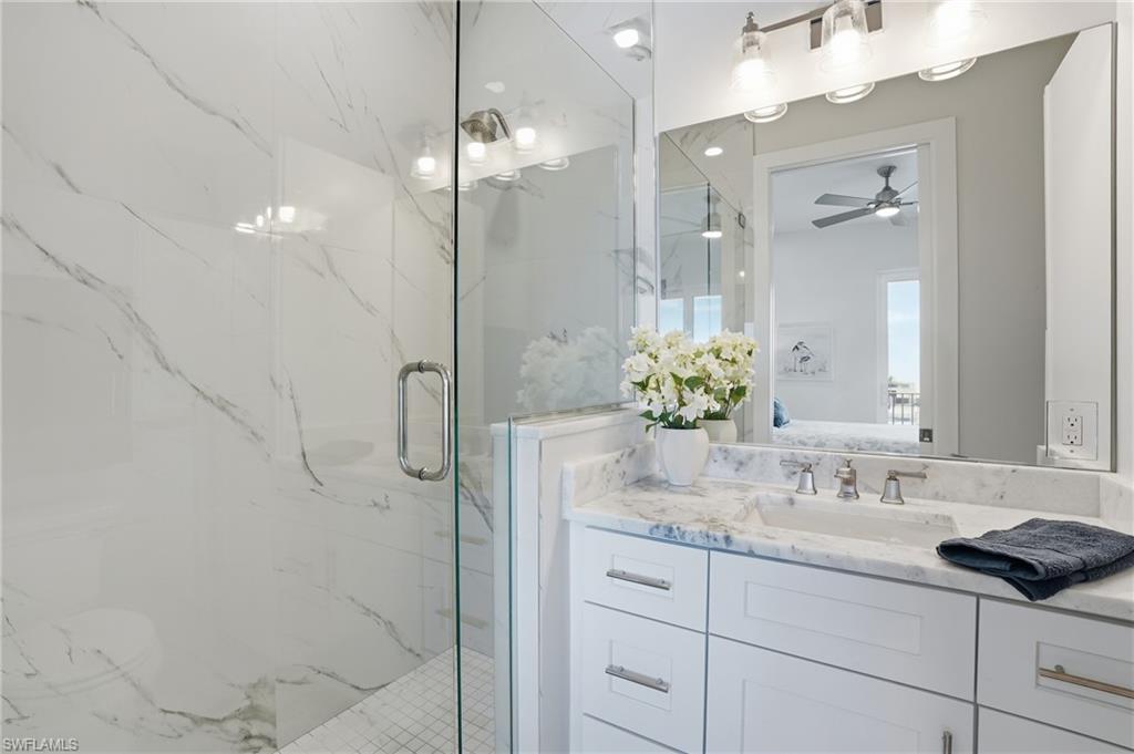 Ensuite bathroom with vanity, a marble finish shower, and a ceiling fan - Virtually Edited Image