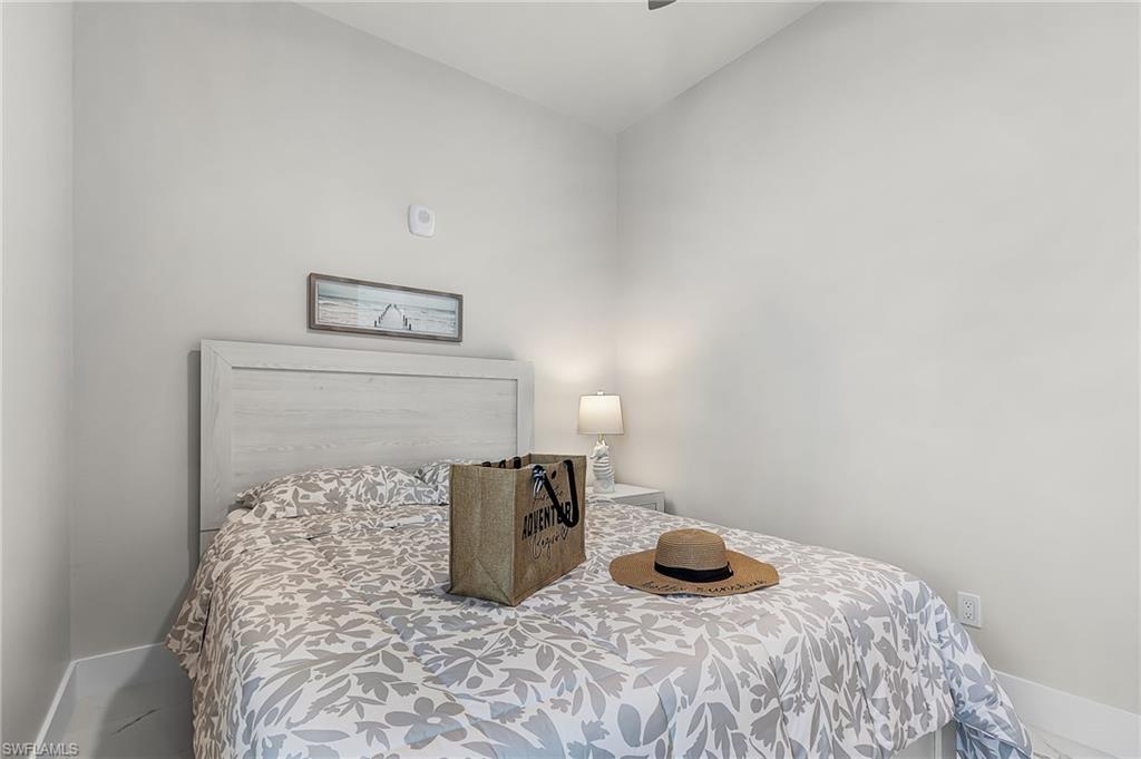 Bedroom featuring a light wood-finish headboard, neutral wall paint, and white baseboards - Virtually Edited Image