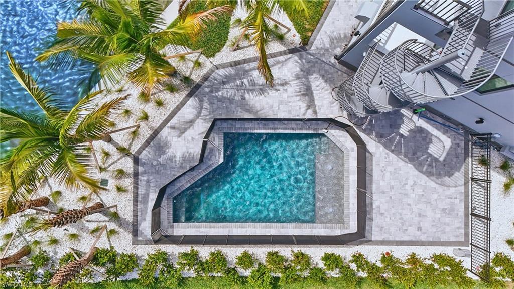 Contemporary swimming pool with integrated spa, surrounded by paver patio and white gravel landscaping - Virtually Edited Image