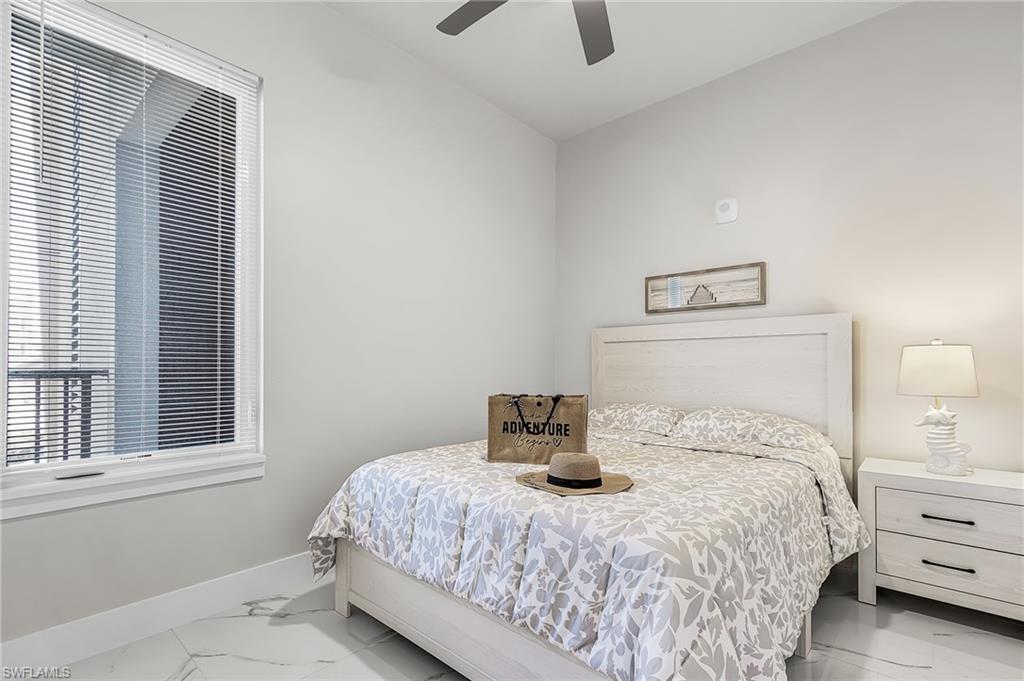Bedroom featuring a large window with horizontal blinds, a ceiling fan, and light-toned wall paint - Virtually Edited Image