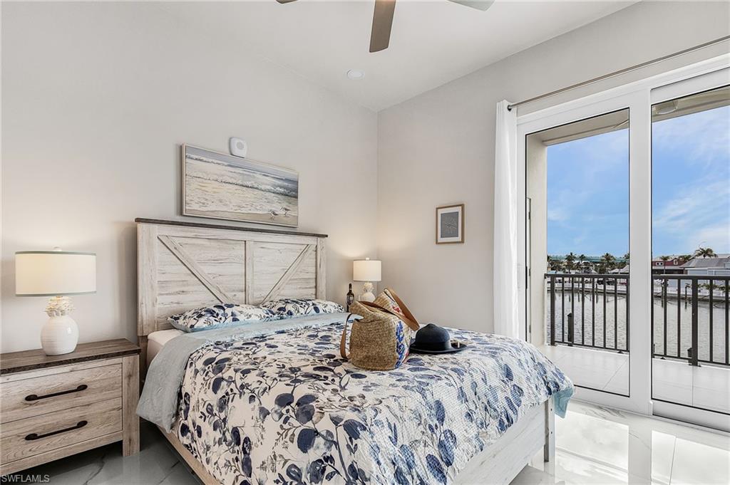 Bedroom featuring large sliding glass doors opening to a balcony with water views - Virtually Edited Image