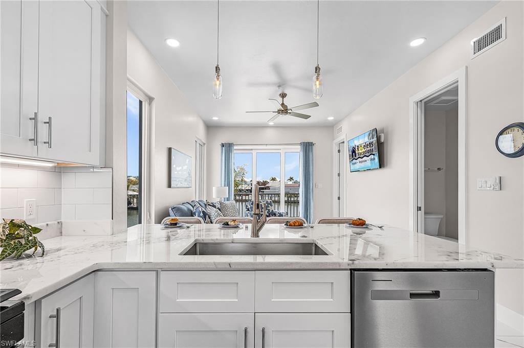 Expansive kitchen island featuring a stainless steel undermount sink, integrated dishwasher, and a light-toned countertop - Virtually Edited Image