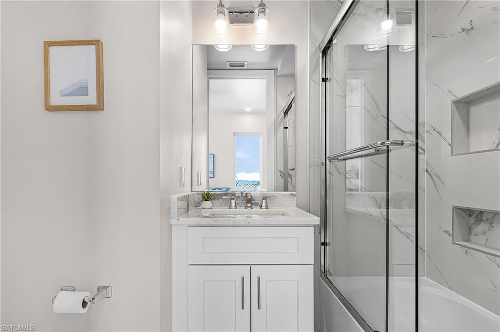 Bathroom featuring a white vanity with a light-toned countertop, a rectangular mirror, and an overhead light fixture - Virtually Edited Image
