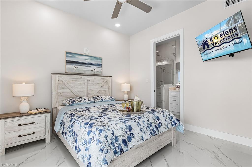 Bedroom with a distressed wood-finish headboard and frame, featuring a ceiling fan, recessed lighting, and large format marble-look floor tiles - Virtually Edited Image