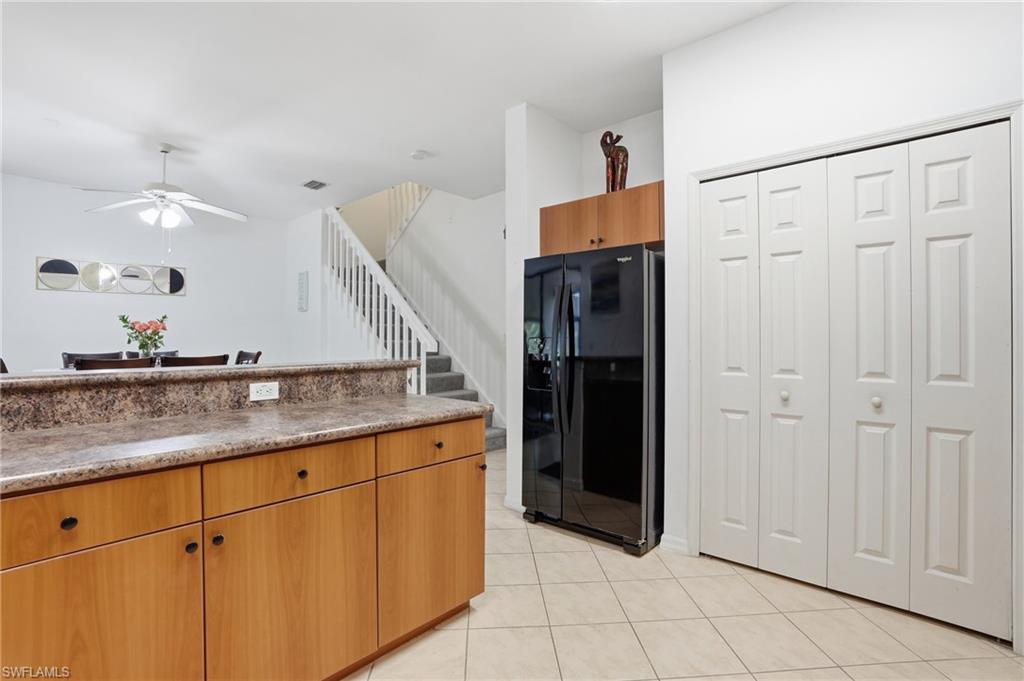 Kitchen area featuring light wood-finish cabinetry, a patterned countertop, pantry and a black refrigerator