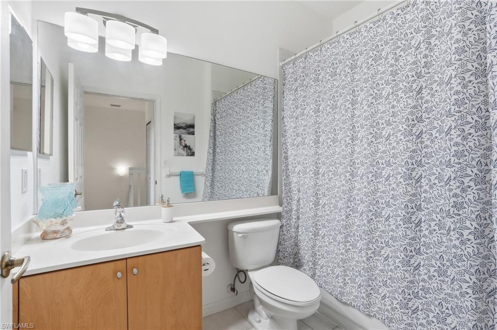 Full-width vanity mirror reflecting overhead light fixture. Shower-tub combination