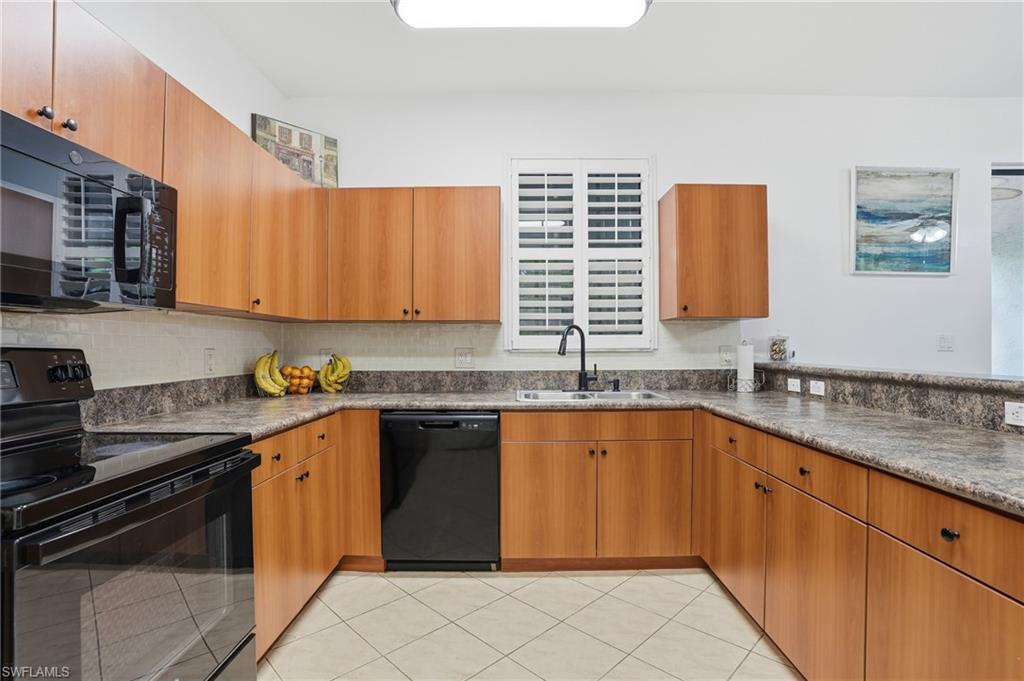 U-shaped kitchen featuring wood-finish cabinetry, black appliances, a double basin sink with a gooseneck faucet, and solid surface countertops