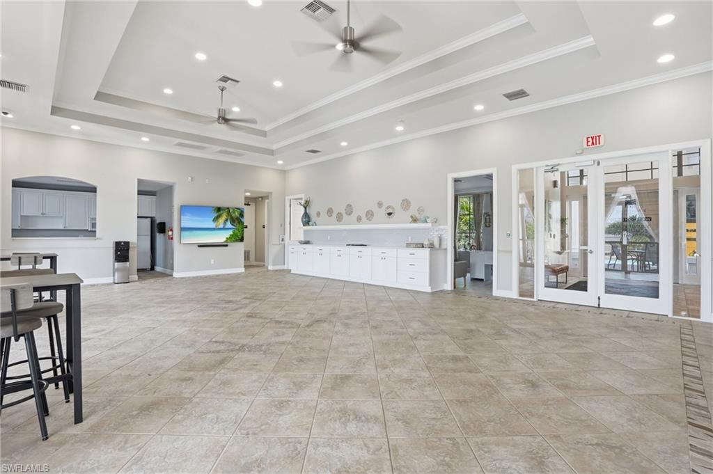 Spacious common area featuring large format tile flooring, recessed lighting, and tray ceilings with ceiling fans