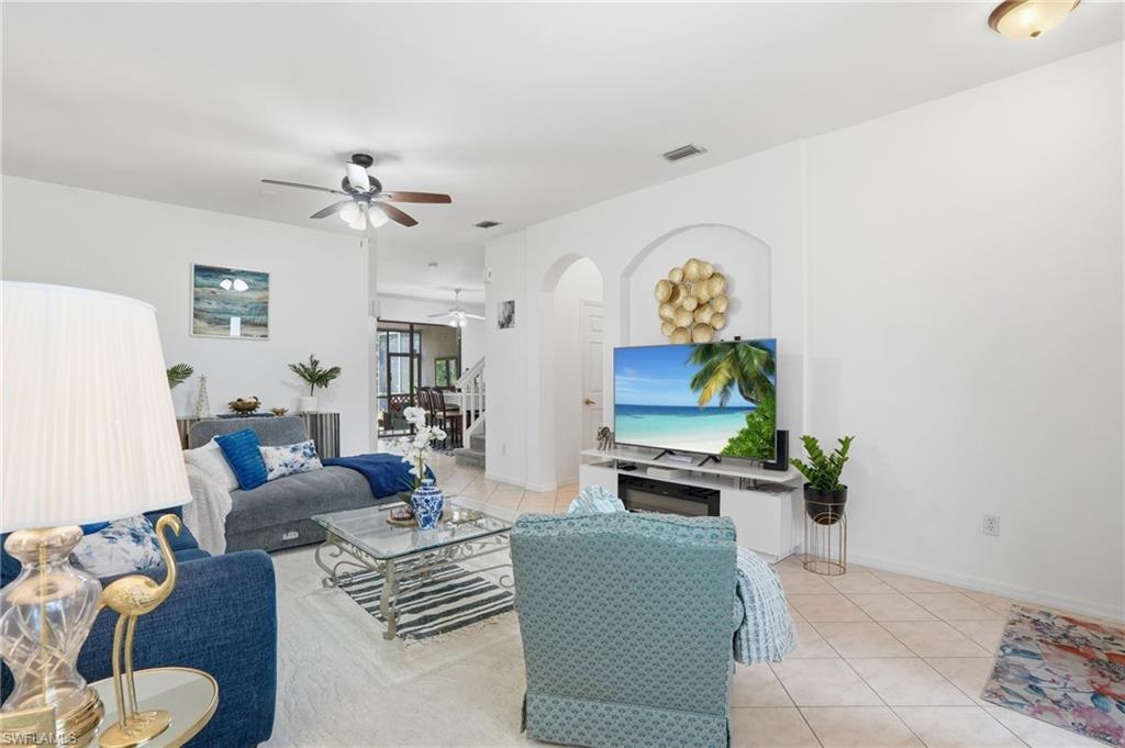 Living area featuring a ceiling fan, light-toned tile flooring, and arched architectural details